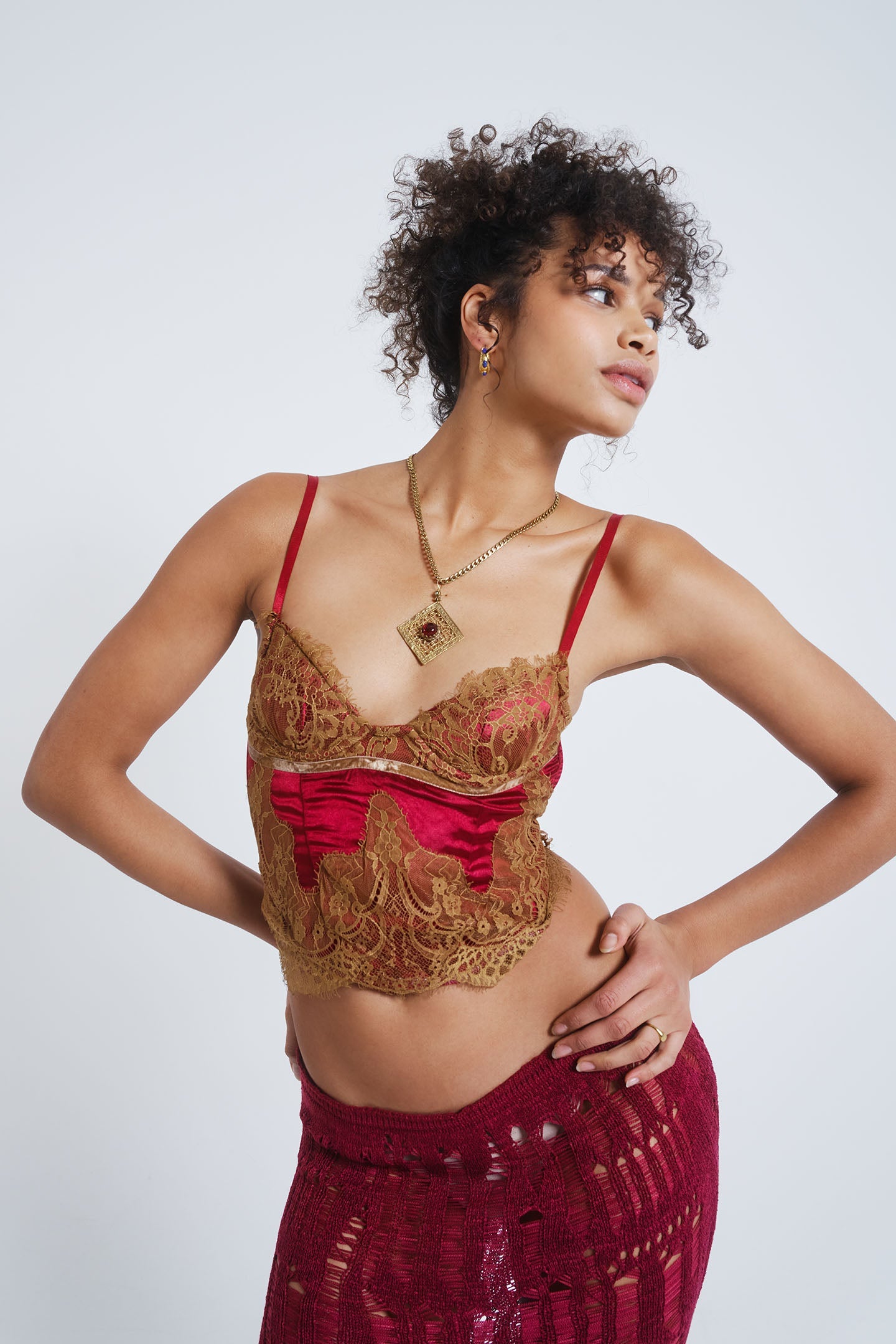 Female model wearing a red satin and mesh corset top with lace detail.  