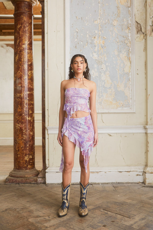 Female wearing Lilac Baroque Printed Asymmetric Mesh Mini Skirt. Styled with the matching asymmetric top. 