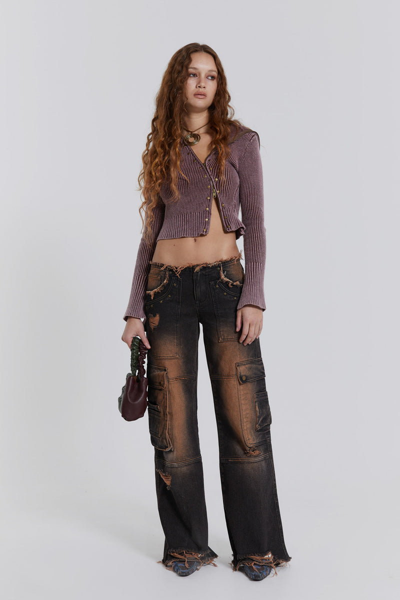 Female model wearing washed black rust cargo denim jeans styled with a brown ribbed knit top.