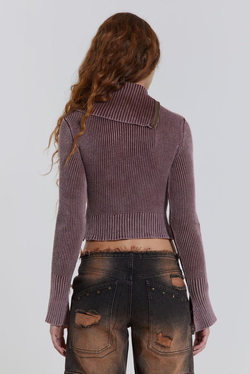 Female model wearing a brown acid wash asymmetric top in ribbed knit. Styled with washed denim jeans. 