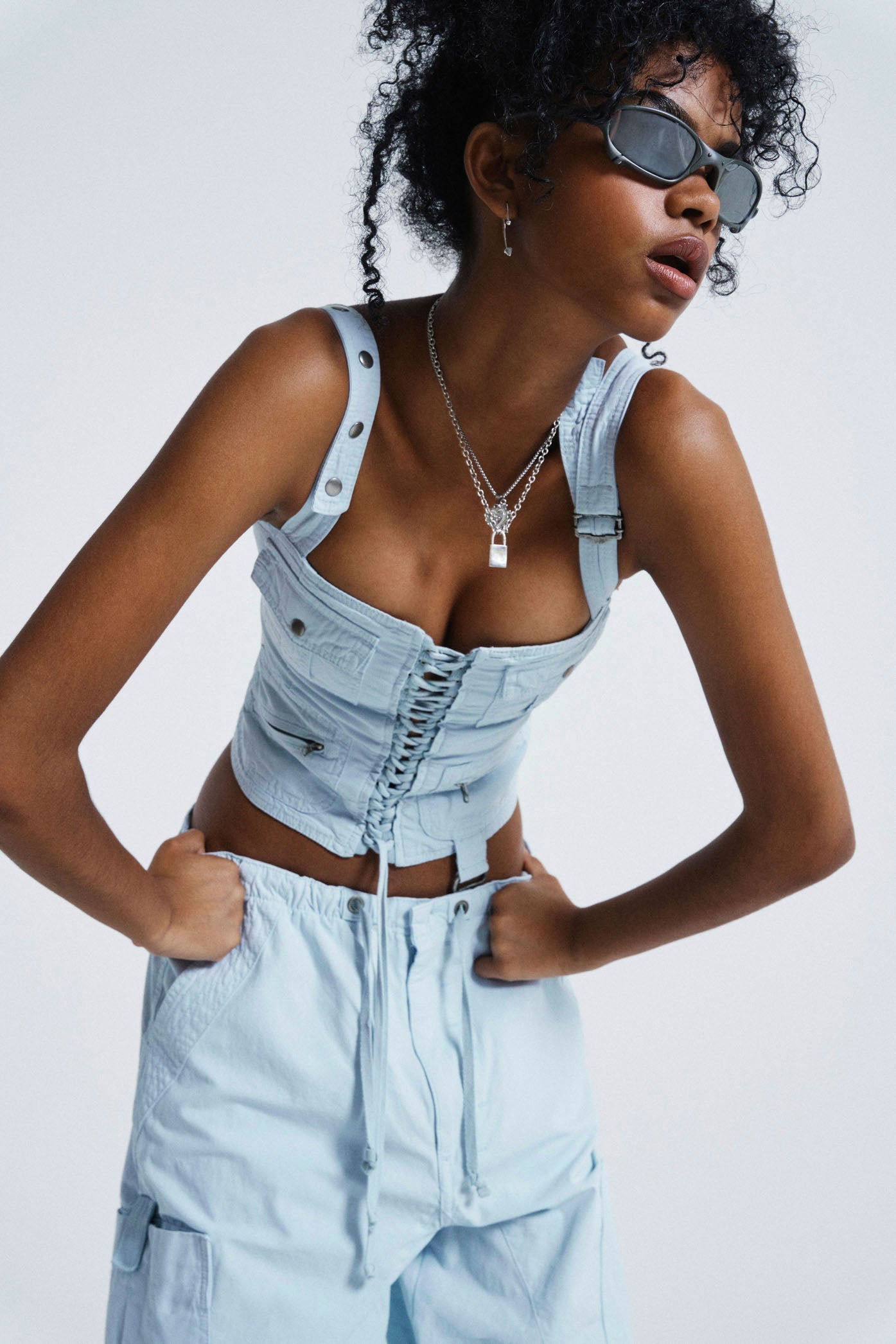 Female wearing Blue Cargo Lace Up Corset Top. Styled with matching parachute pants. 