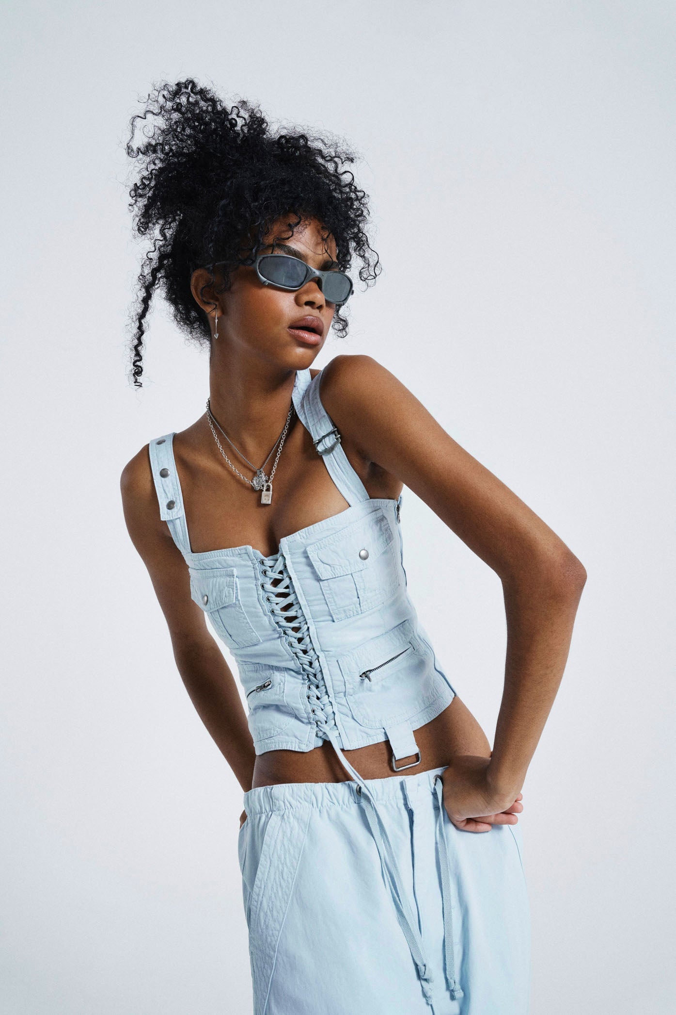 Female wearing Blue Cargo Lace Up Corset Top. Styled with matching parachute pants. 