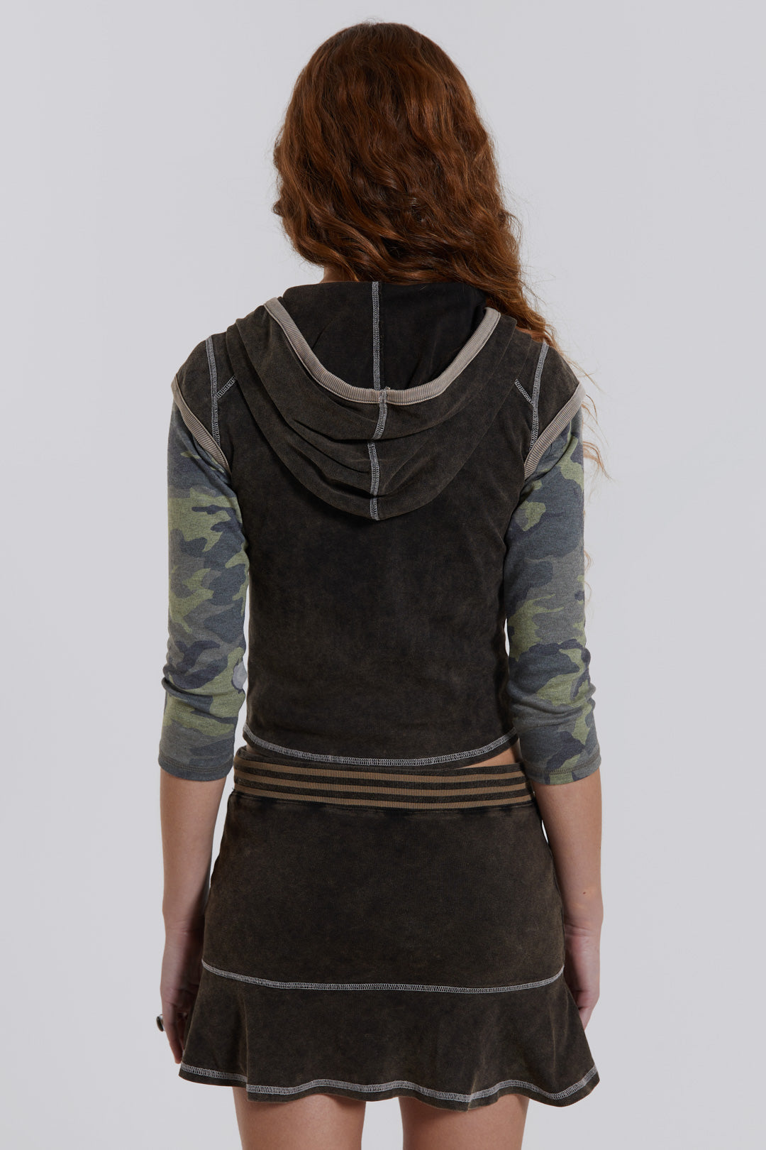 Female model wearing a washed brown sporty mini skirt with frill hem. Styled with the matching cap sleeve top. 