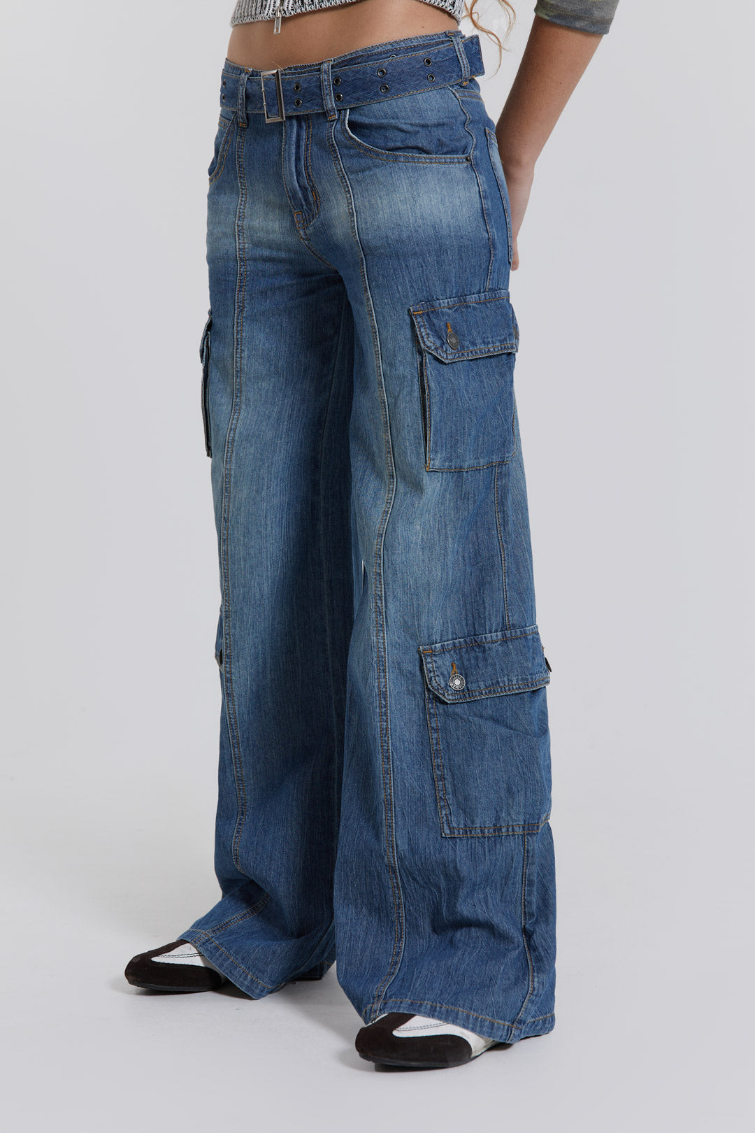 Female model wearing blue washed chambray denim skater fit jeans with belt detail. 