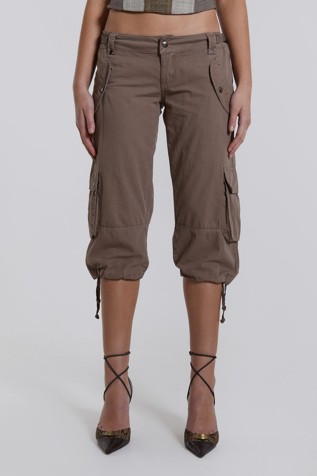 Female model wearing walnut cropped cargo trousers with a drawcord hem detail. Paired with a check corset top. 