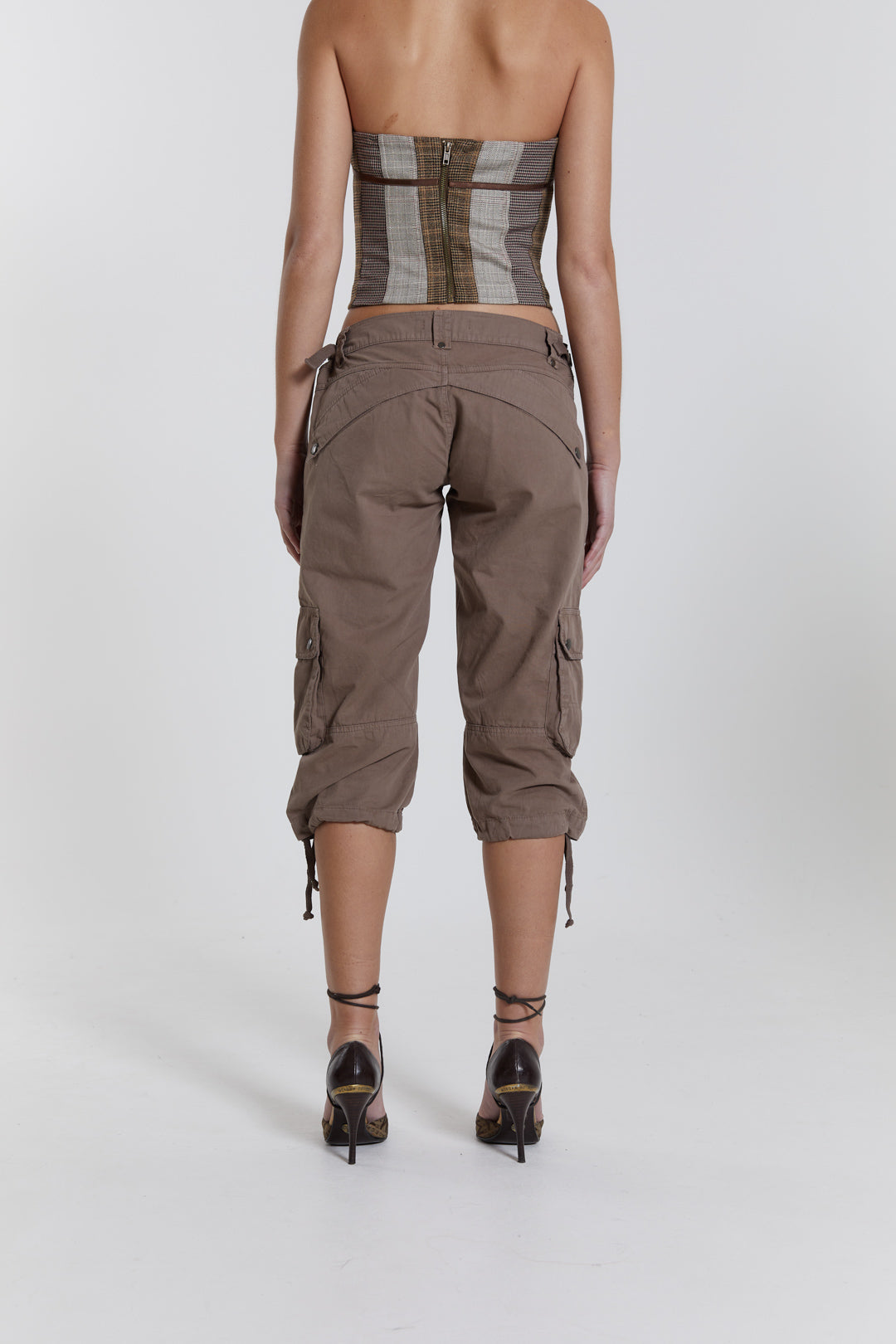 Female model wearing walnut cropped cargo trousers with a drawcord hem detail. Paired with a check corset top. 