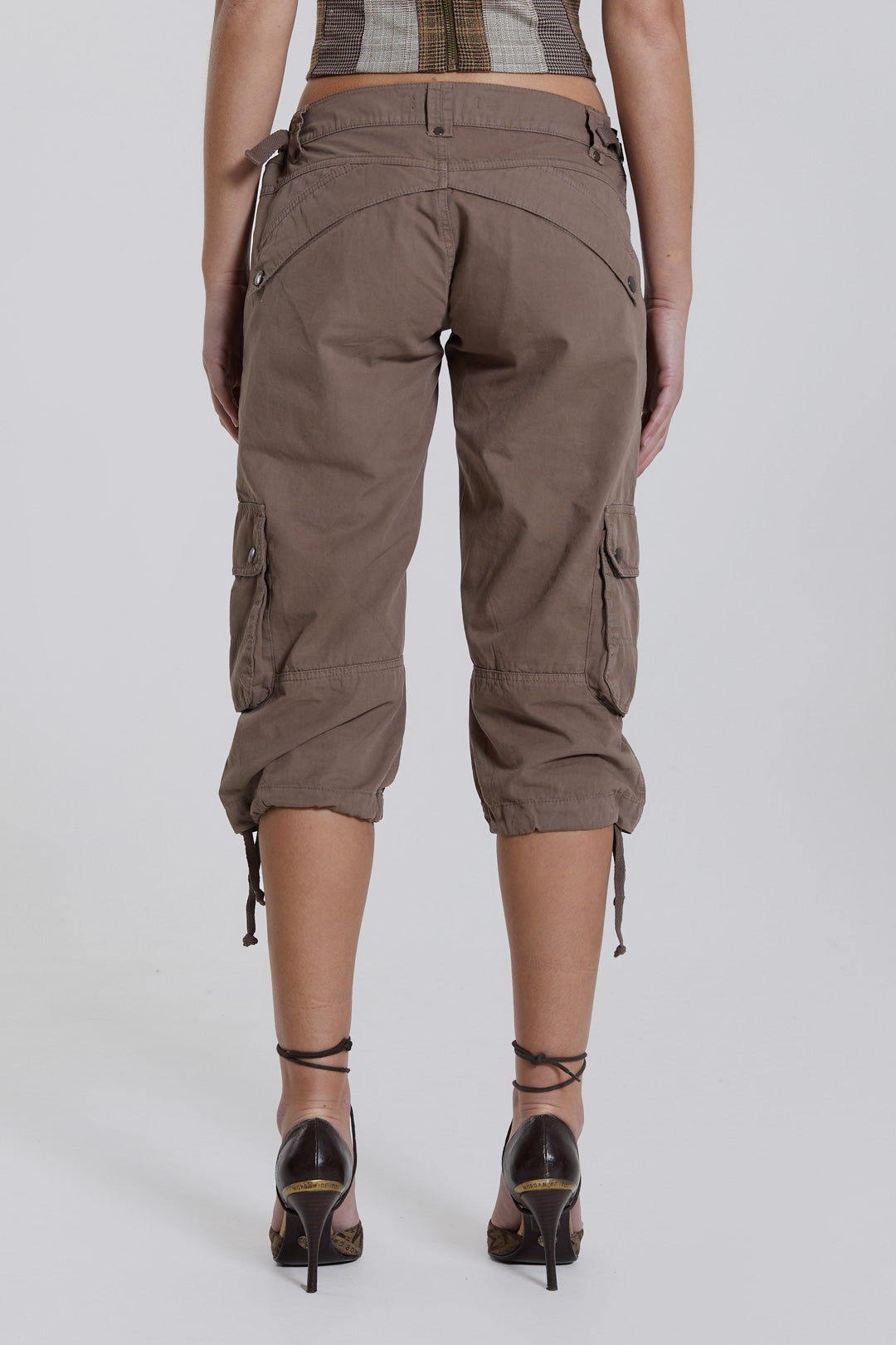 Female model wearing walnut cropped cargo trousers with a drawcord hem detail. Paired with a check corset top. 