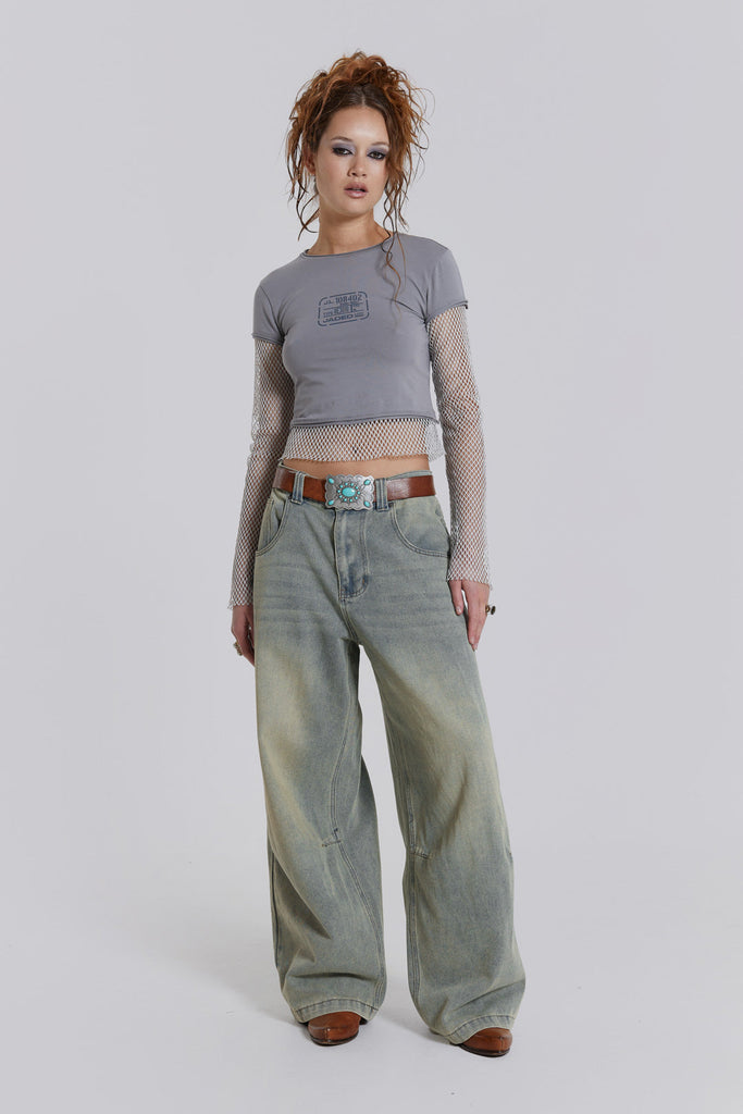 Female model wearing light was colossus fit jeans, styled with a grey top. 