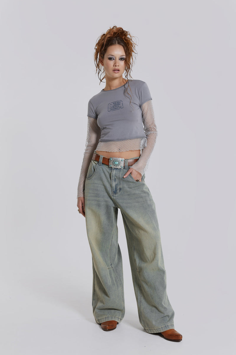 Female model wearing light was colossus fit jeans, styled with a grey top. 