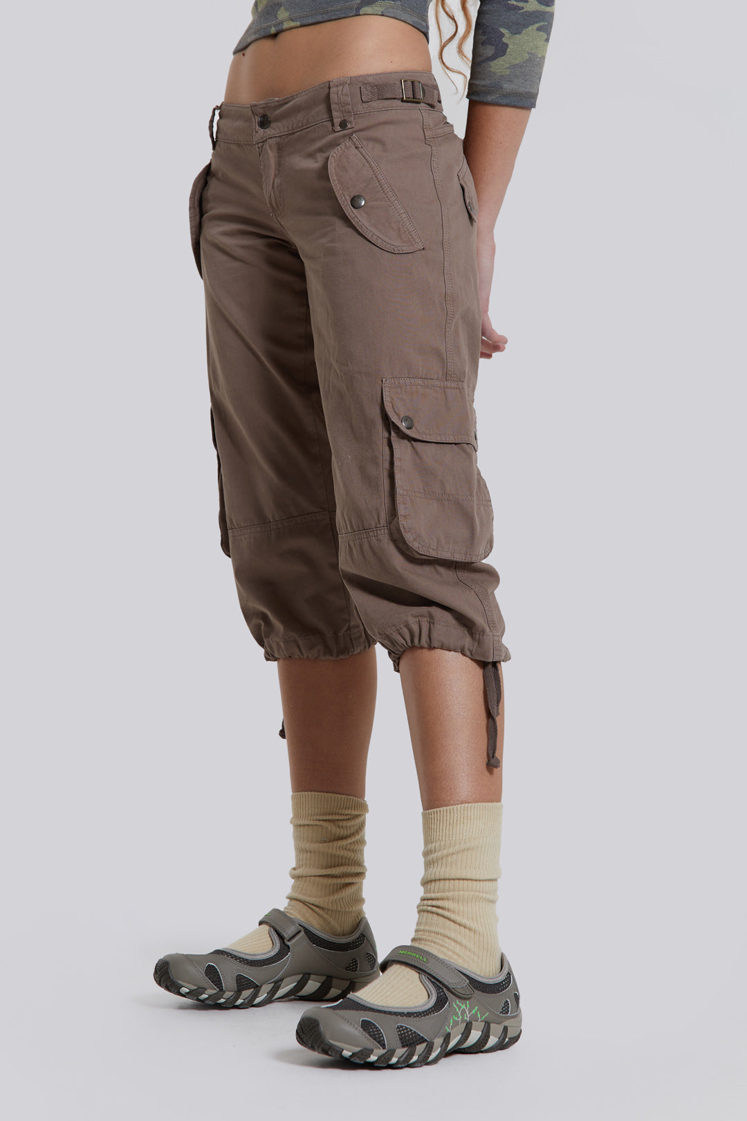 Female model wearing walnut cropped cargo trousers with a drawcord hem detail. Paired with a check corset top. 