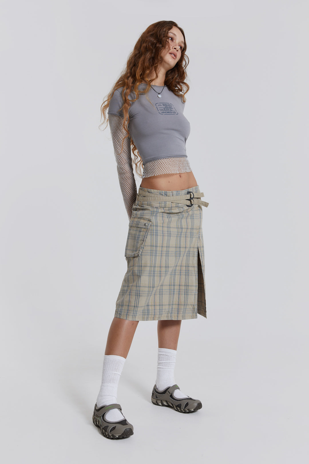 Female model wearing a grey t-shirt with long contrast mesh sleeves, styled with a check midi skirt. 