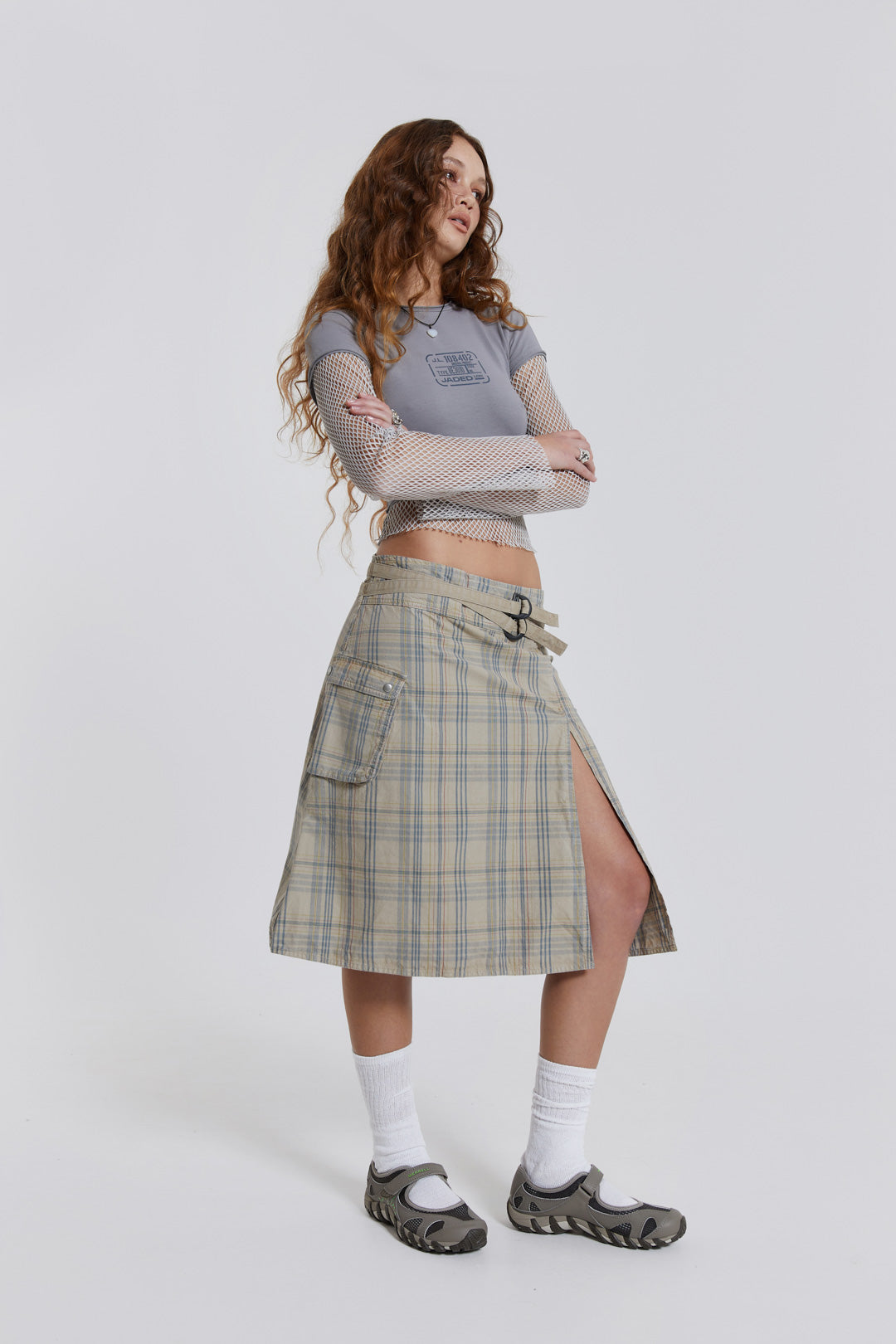 Female model wearing a grey t-shirt with long contrast mesh sleeves, styled with a check midi skirt. 