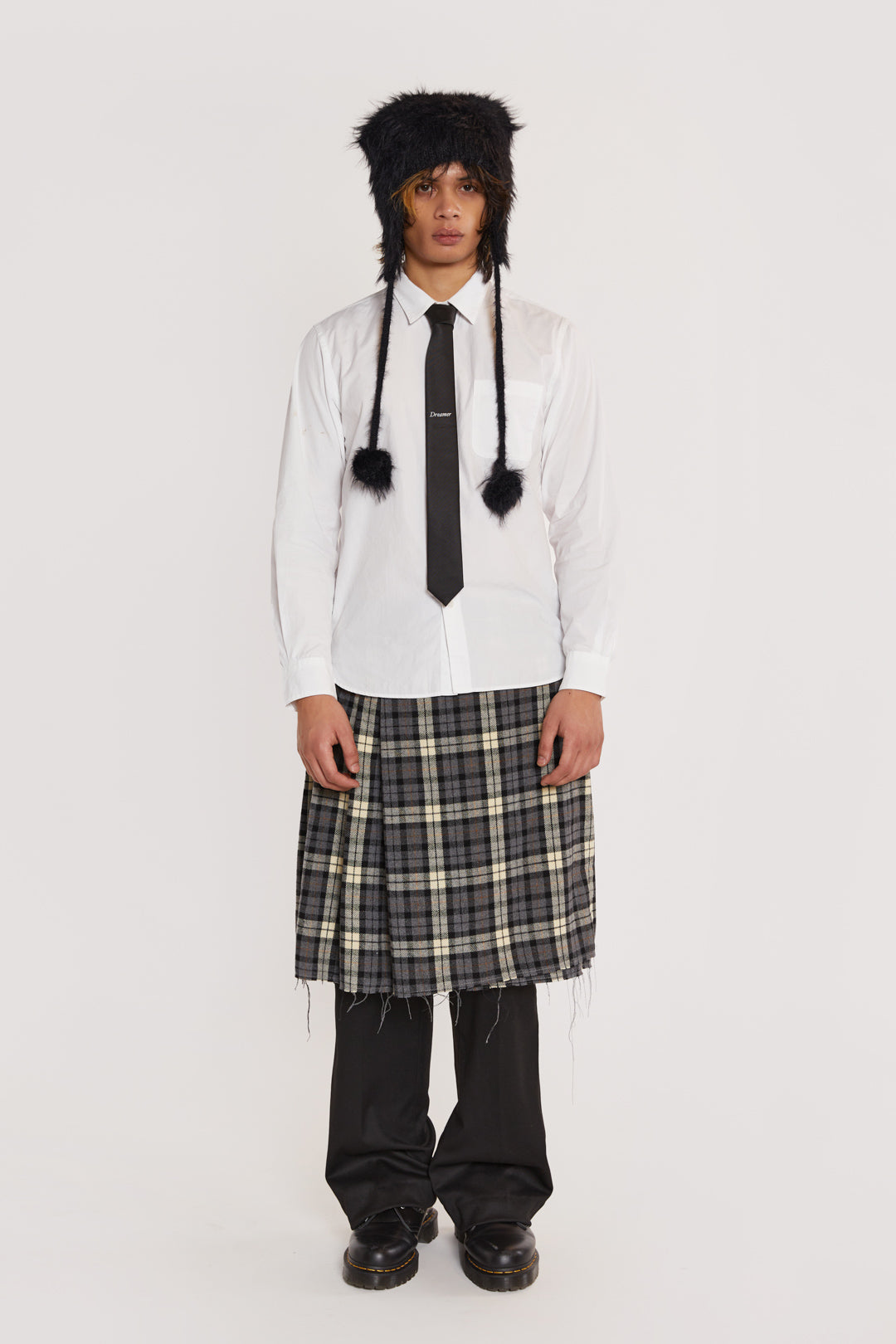 Male wearing Grey Checked Kilt. Styled with black suit trousers and white shirt. 