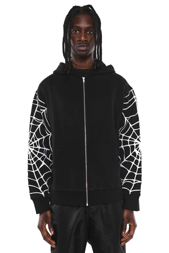 Black oversized zip up hoodie with spider print sleeves. Styled with black jeans. 