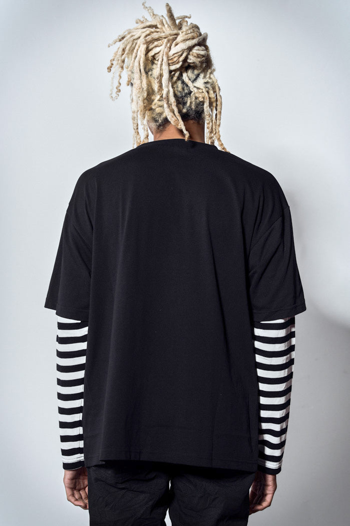 Back view of black oversized long sleeve tshirt with graphic print and mock stripe layered sleeves