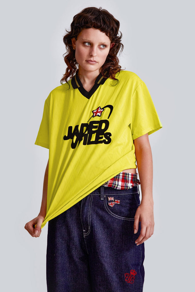 Female wearing a yellow jacquard argyll short sleeve football shirt with Jaded x VFiles logo. 