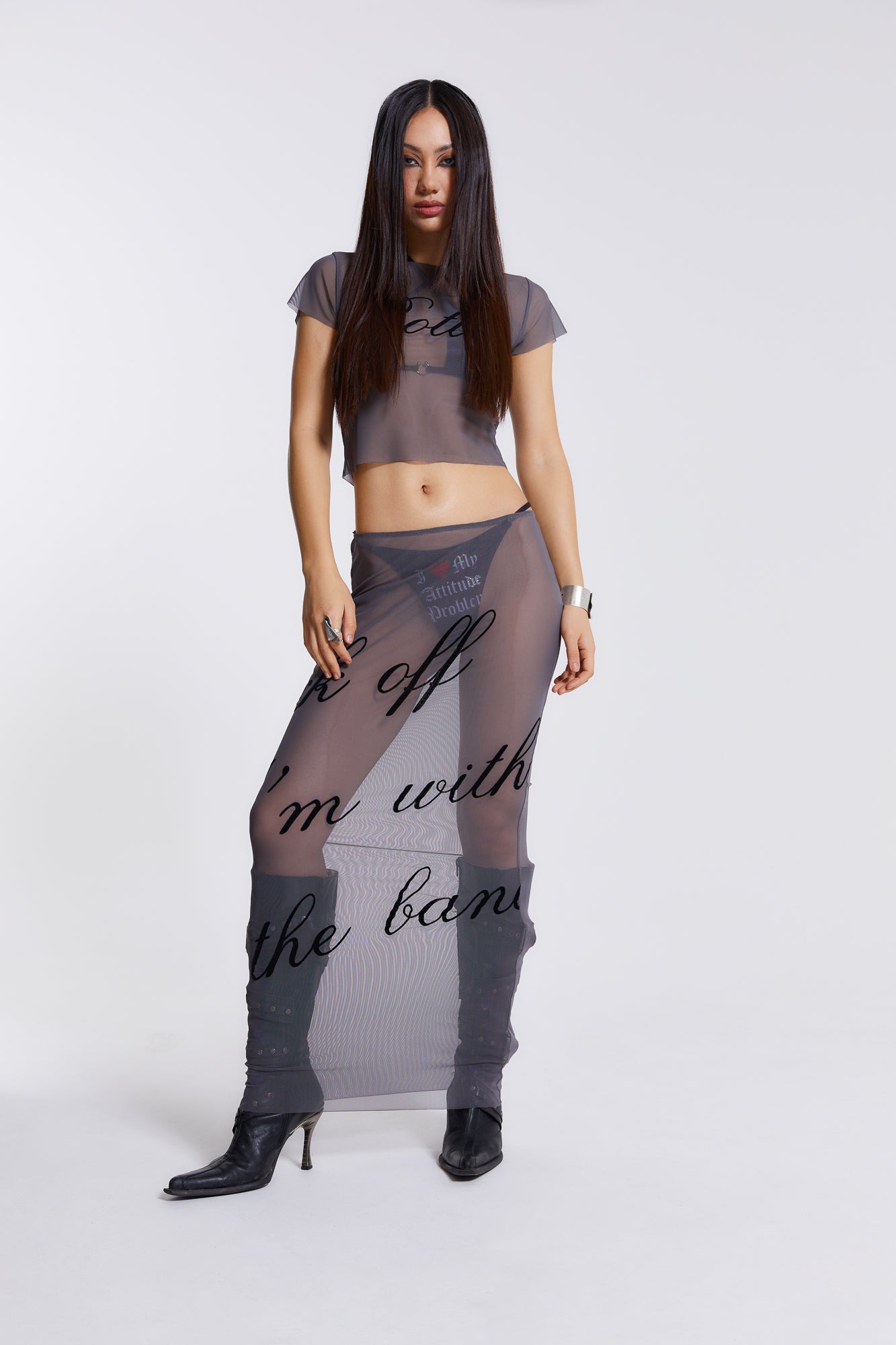 Female model wearing grey lightweight mesh t-shirt features a “rotten” black flock placement print. Paired with the matching mesh maxi skirt. 