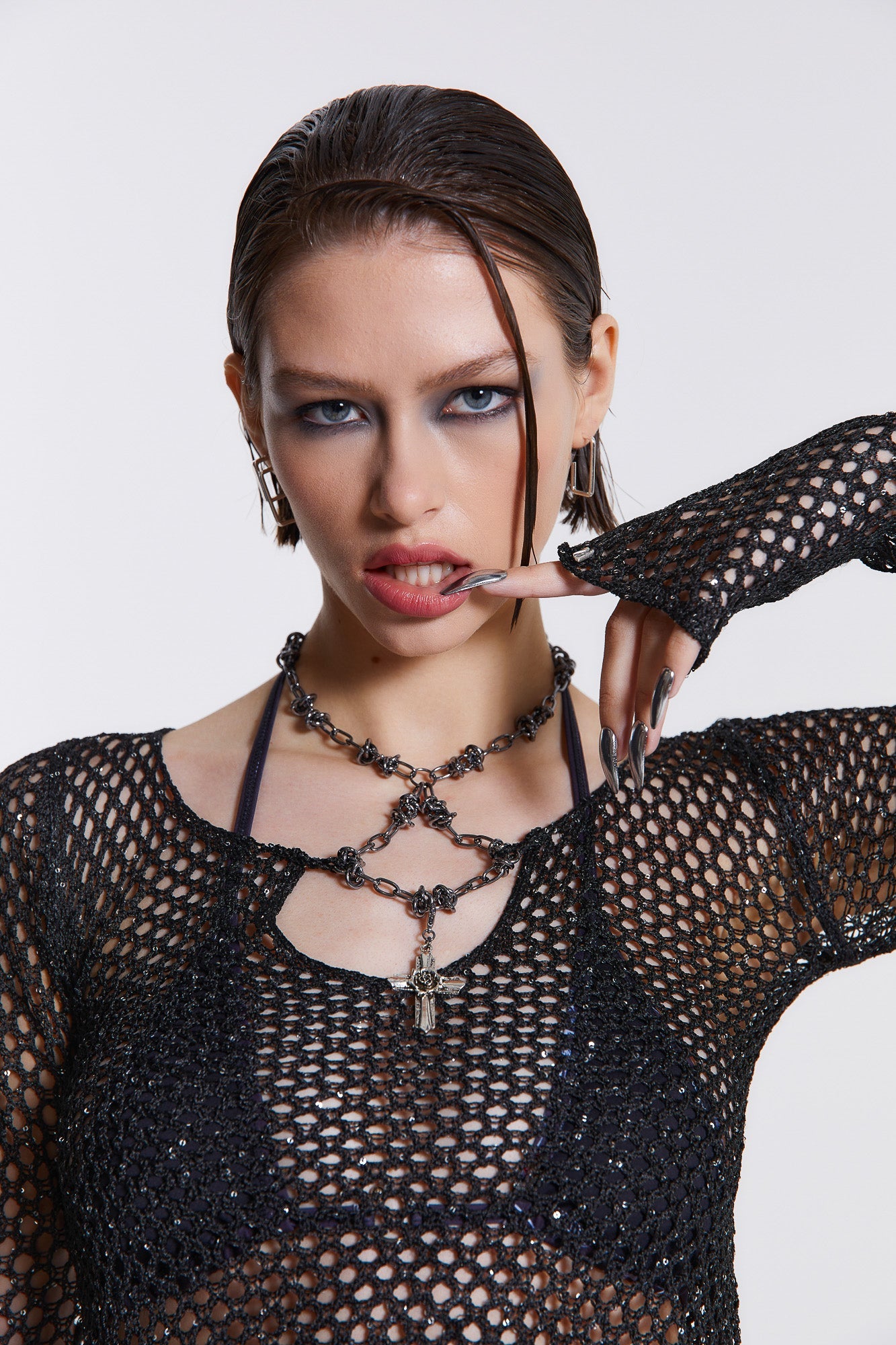 Female model wearing black sequin crochet top which features an attached beaded necklace. The flared sleeves and cropped length can be seen throughout the Vendetta collection. Paired with black wide leg trousers. 