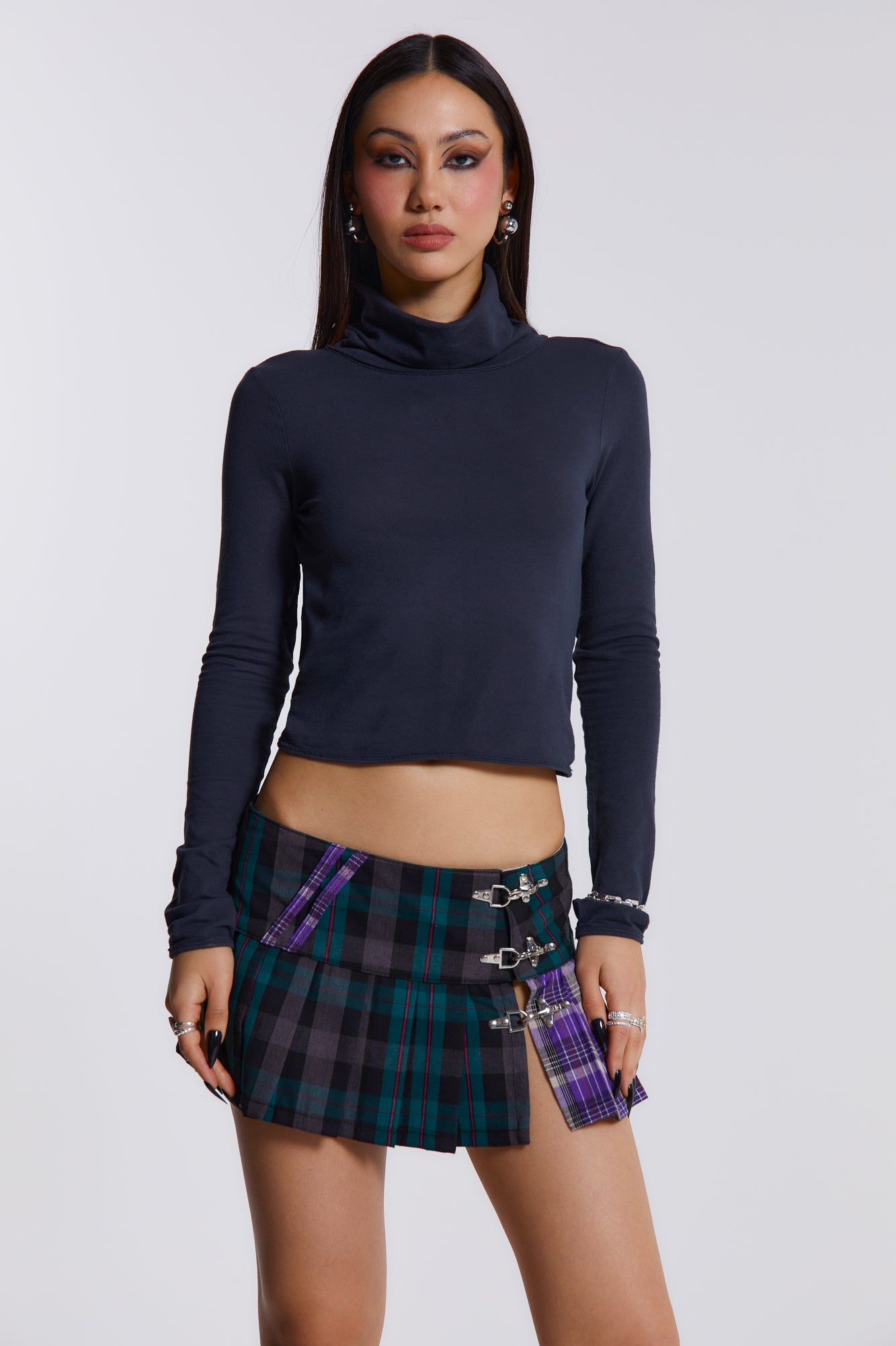 Female model wearing blue, green and purple checked mini kilt with pleats and buckle detail. 