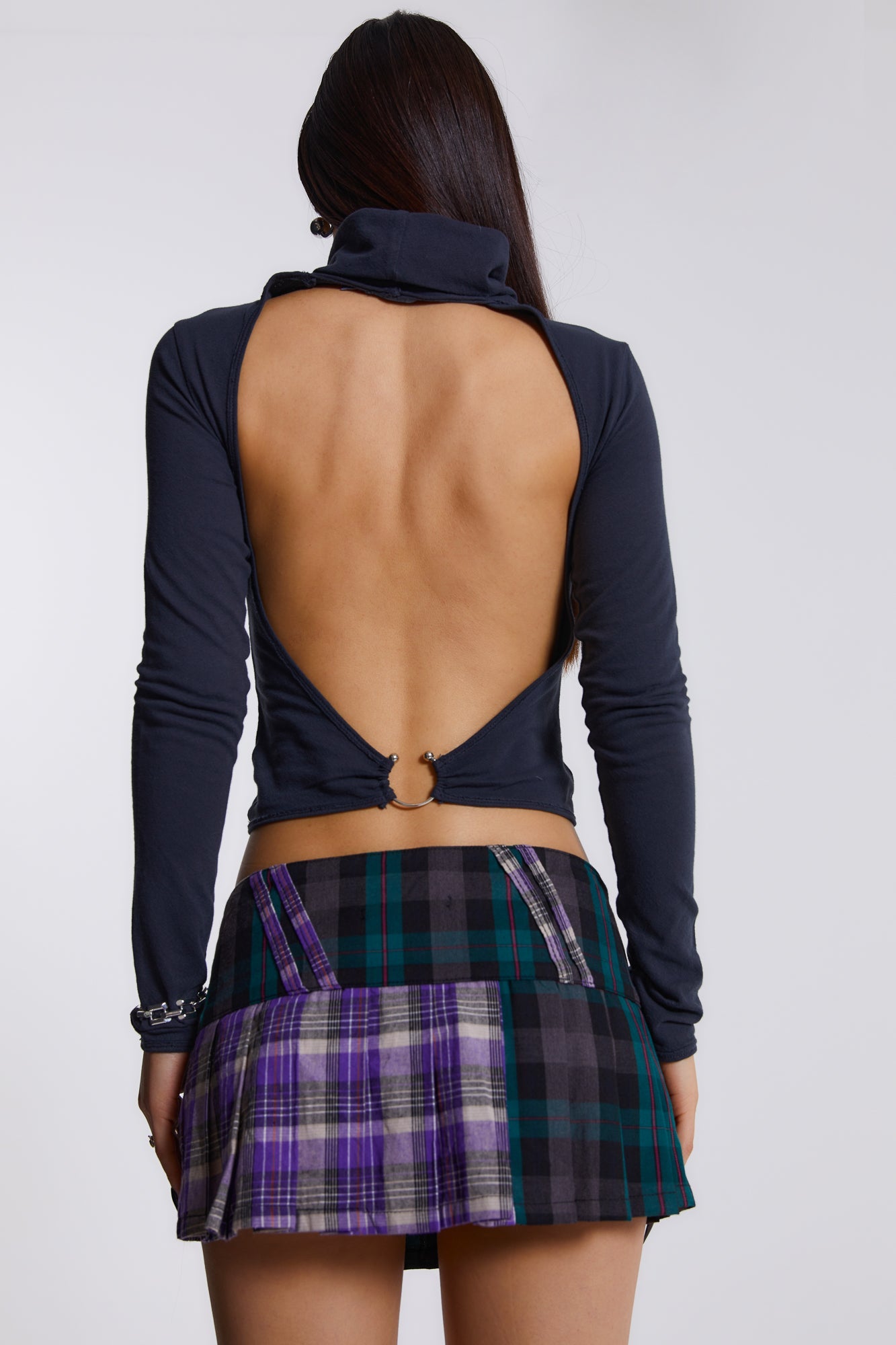 Female model wearing blue, green and purple checked mini kilt with pleats and buckle detail. 