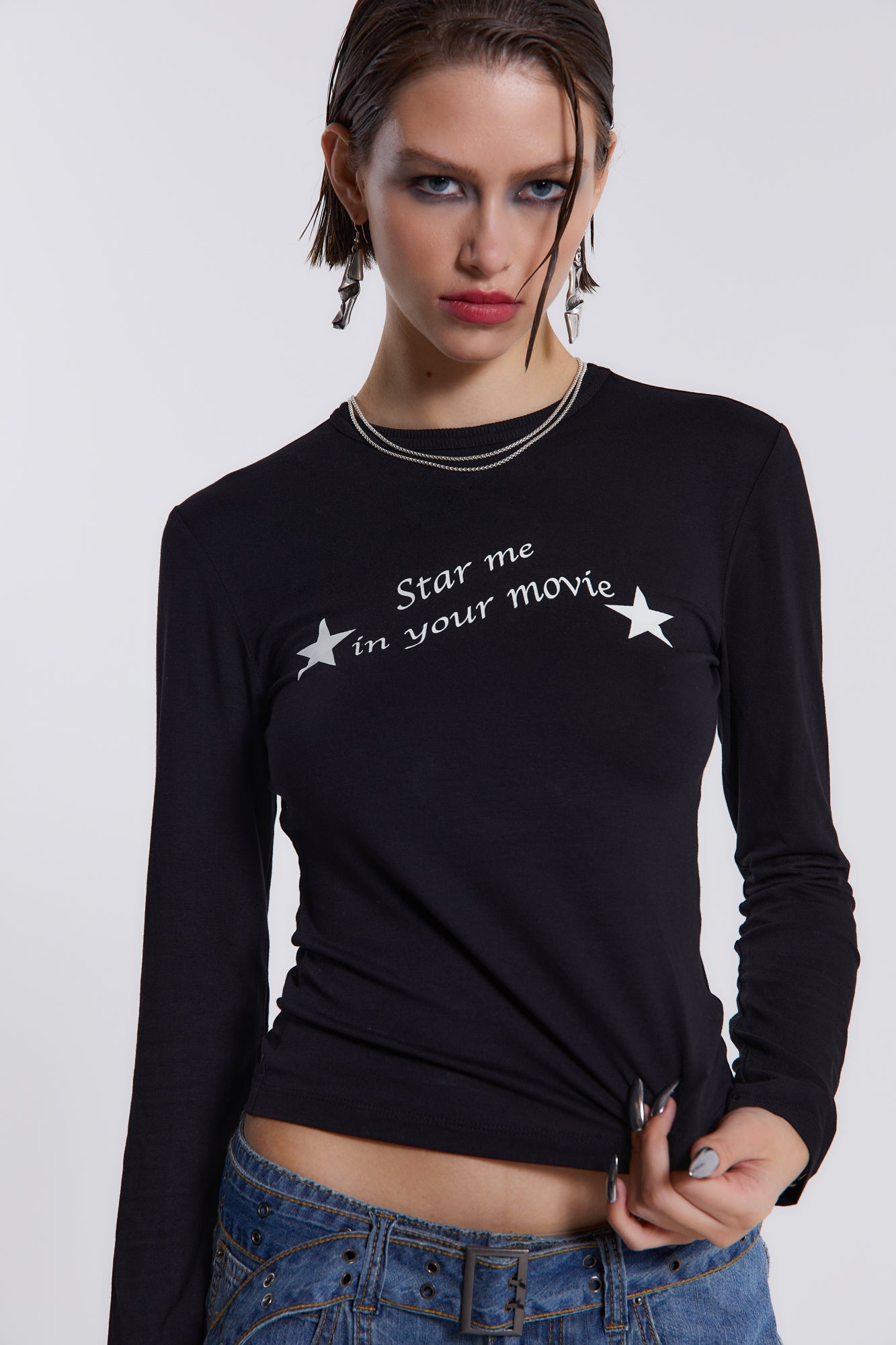 Female model wearing This black long sleeve top features a white movie star screen print graphic across the chest. 