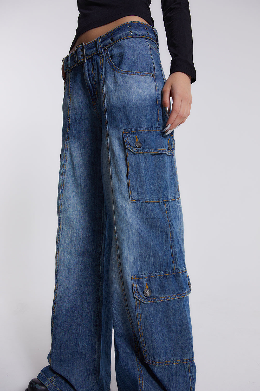 Female model wearing blue washed chambray denim skater fit jeans with belt detail. 