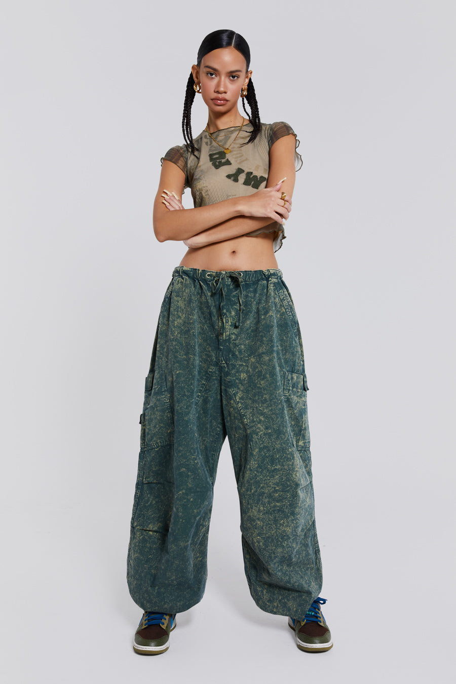 Female wearing green acid wash parachute cargo pants styled with a khaki green mesh short sleeve t-shirt.