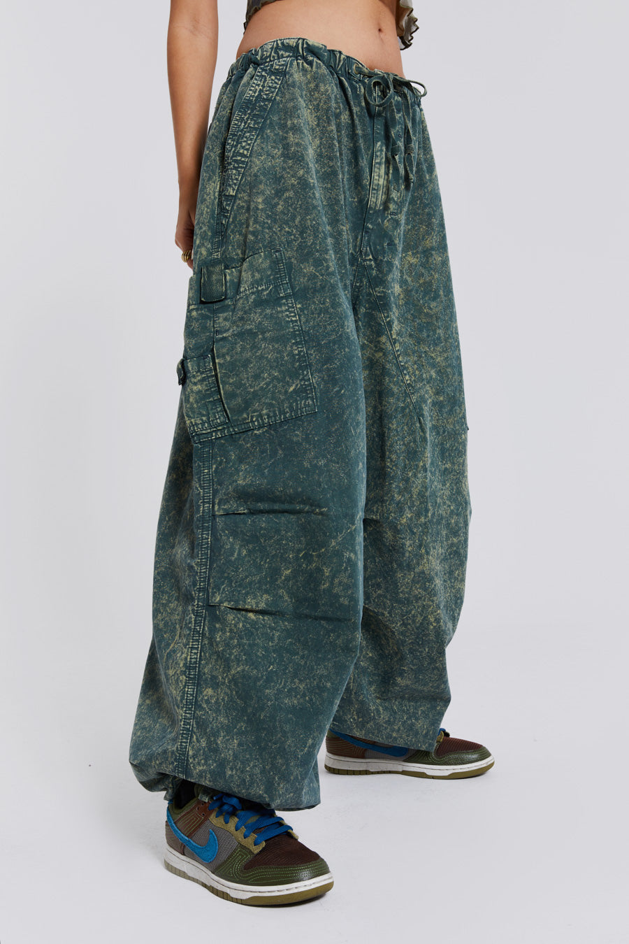 Female wearing green acid wash parachute cargo pants. 