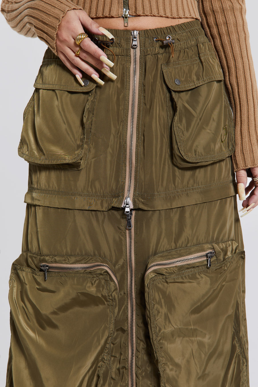 Female wearing a shiny khaki green pocket detail cargo midi skirt. Styled with a khaki green cargo jacket. 