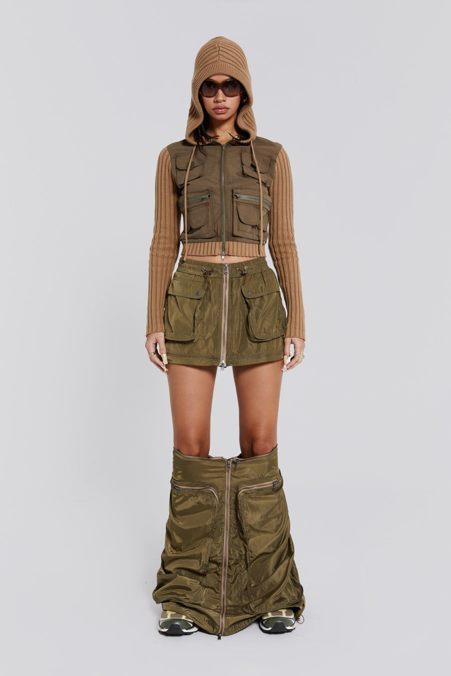 Female wearing a shiny khaki green pocket detail zip off cargo midi skirt. Styled with a khaki green cargo jacket. 