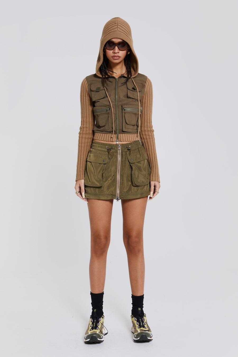 Female wearing a shiny khaki green pocket detail zip off cargo mini skirt. Styled with a khaki green cargo jacket. 