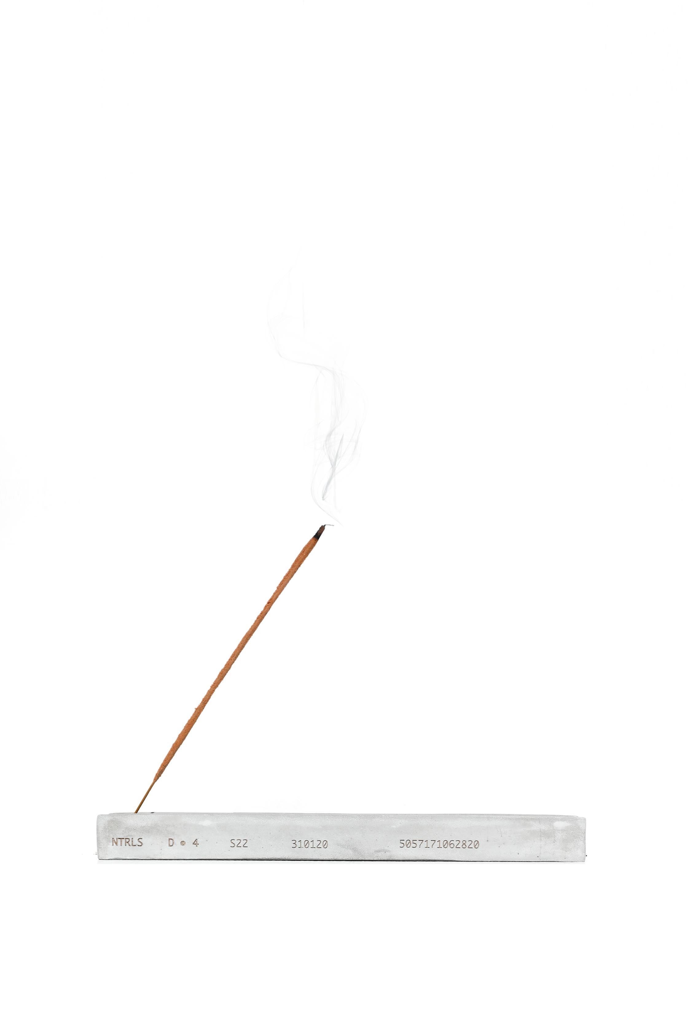 NTRLS branded concrete incense stand with burning incense. 