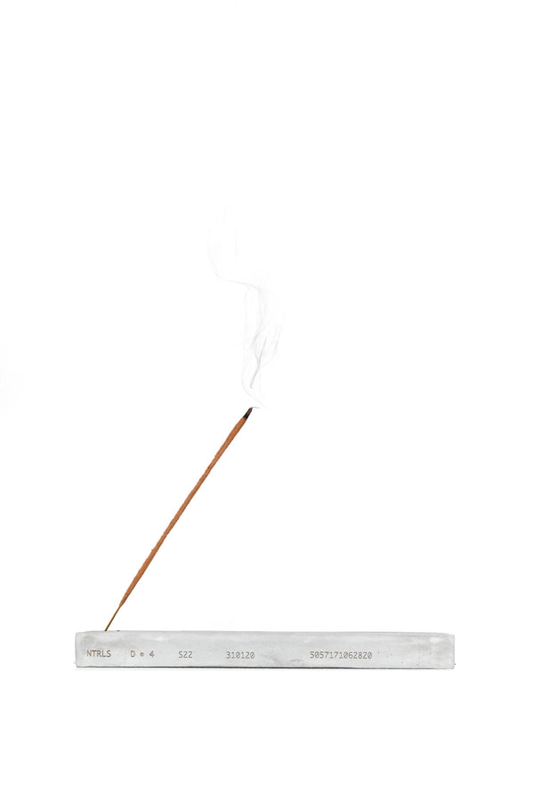 NTRLS branded concrete incense stand with burning incense. 