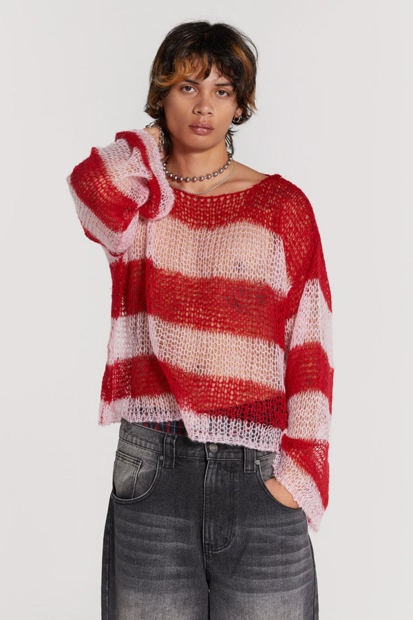 Male wearing red and pink striped loose fitted knitted jumper. Styled with black colossus jeans. 