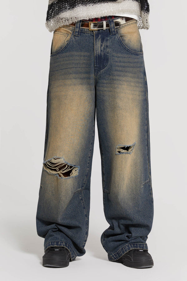 Male wearing sandblast blue denim jeans in a busted colossus mid-rise fit with double knee rips. 