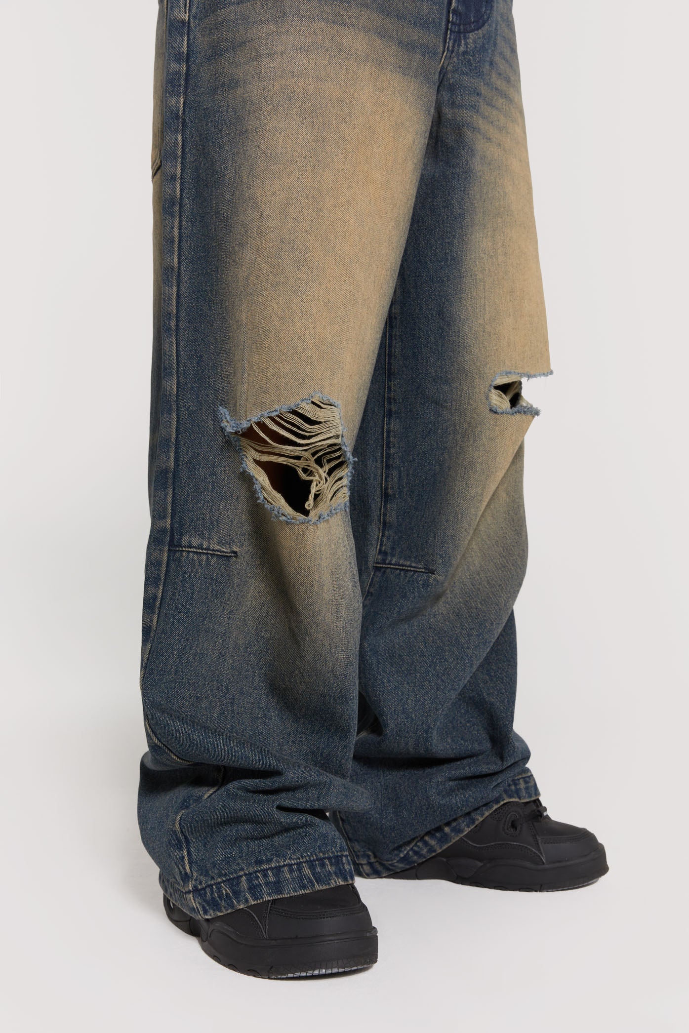 Male wearing sandblast blue denim jeans in a busted colossus mid-rise fit with double knee rips. 