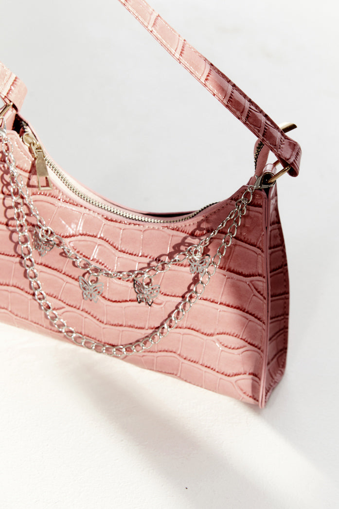 Baby pink crocodile effect shoulder bag with silver butterfly chain detail.